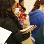 Journalism students take notes under the grand staircase.